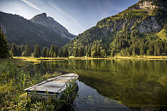 Lake Lauenen in autumn with mountains in the background. A rowing boat can still be seen in the foreground.