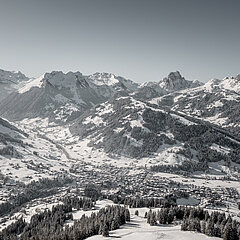 Panoramic view of the village of Gstaad in winter, with the Eggli and other mountains in the background.