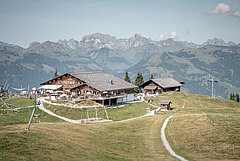 Mountain restaurant on Wispile in summer, surrounded by green meadows and overlooking the surrounding alpine mountain ranges.