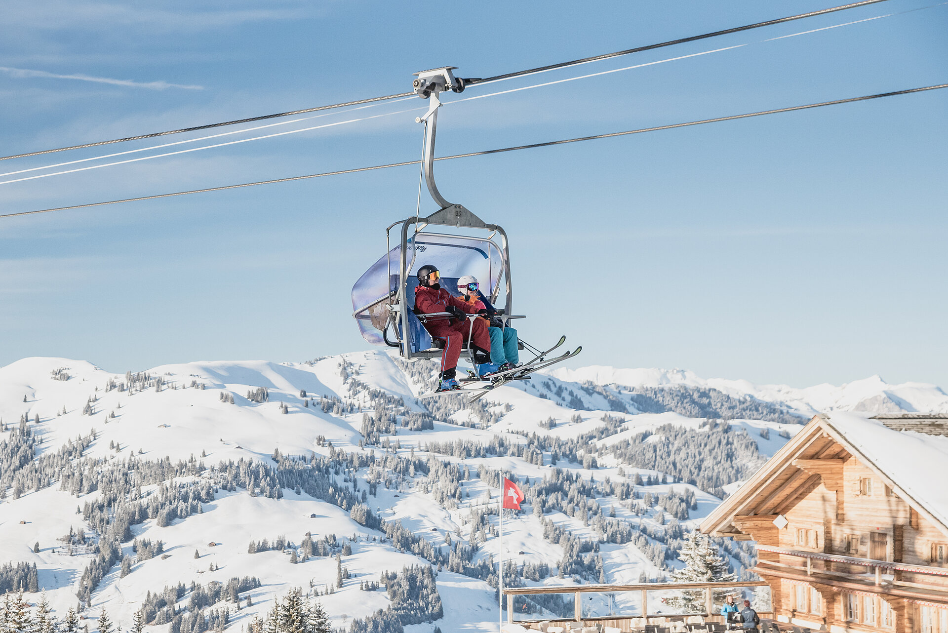 Sessellift mit 2 Skifahrern und verschneiter Aussicht.&nbsp;