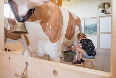 Un enfant trait la vache artificielle