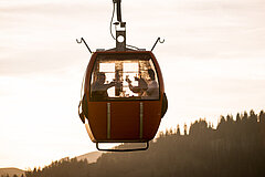  Dans l’ambiance du soir, quatre personnes trinquent avec des verres de vin dans une télécabine rouge.