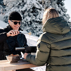 Zwei Personen am Käse-Fondue essen in winterlichen Landschaft